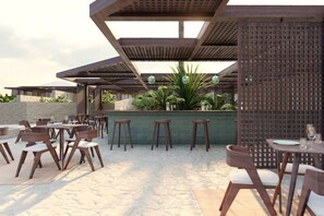 An outdoor patio with multiple tables and chairs, a bar area, and a decorative wall with a lattice pattern. - Meerum 3 A Private Beachfront Sanctuary by Domisi (Pigianos Kampos)