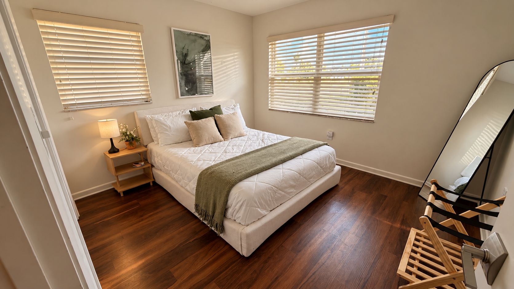 Un dormitorio con cama, mesita de noche, lámpara y espejo.