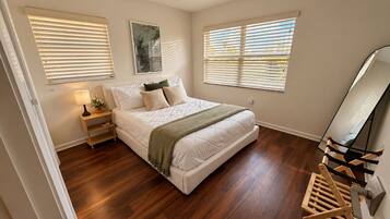 Un dormitorio con cama, mesita de noche, lámpara y espejo.