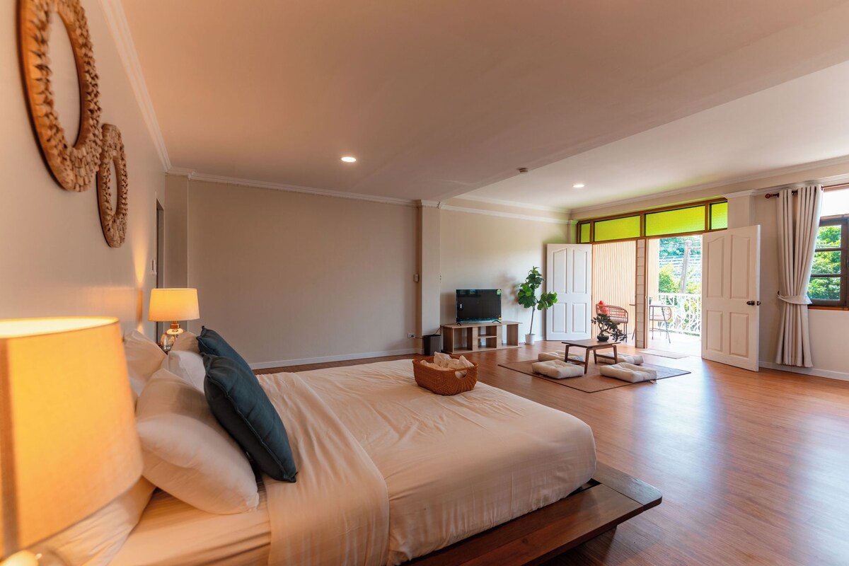 Quarto espaçoso com uma cama grande, televisão e varanda com vista.
