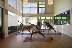 Um quarto amplo com grandes janelas, piso de madeira e um espaço para yoga.