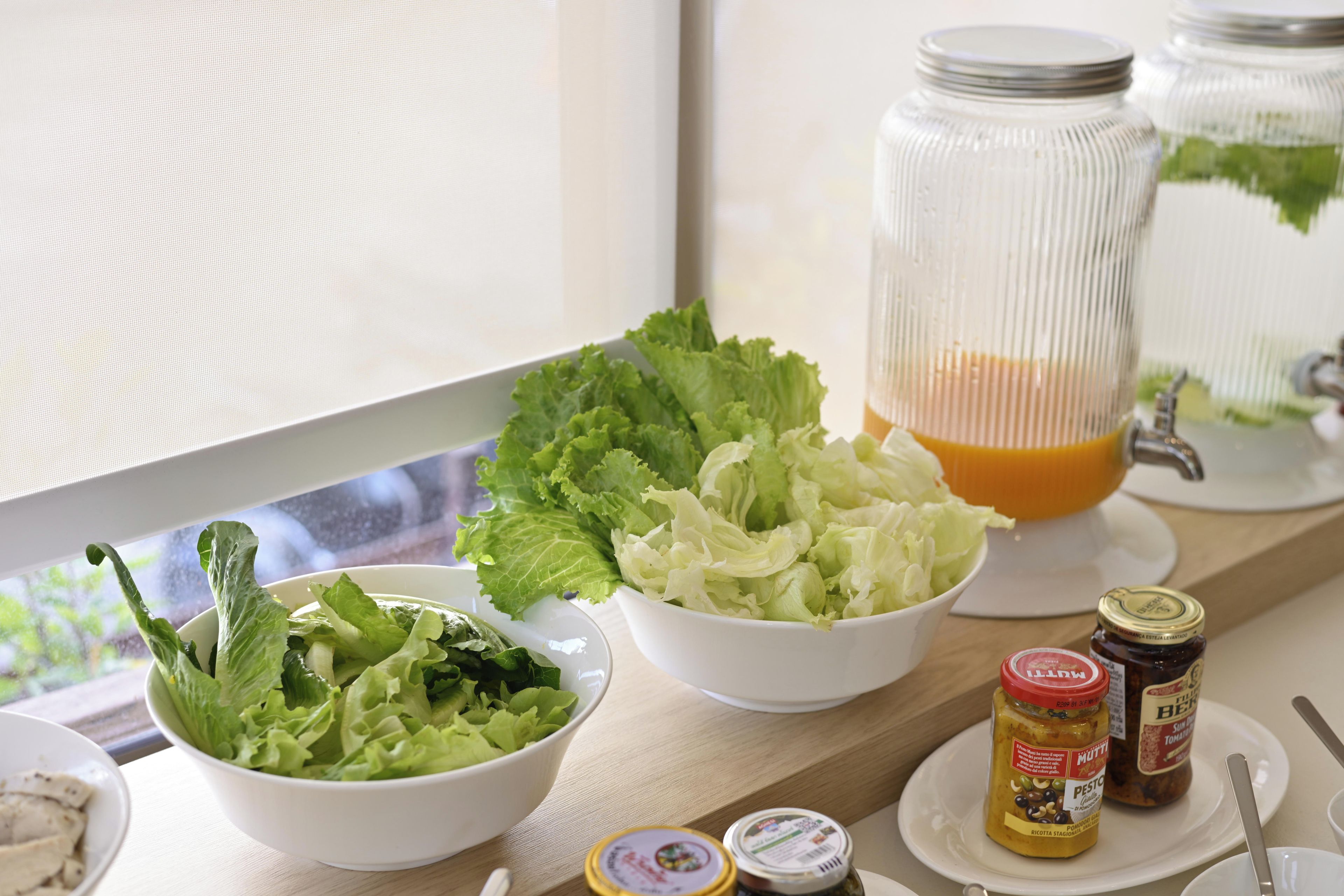 Una mesa con ensaladas en cuencos, un tarro de cristal con una bebida y salsas.