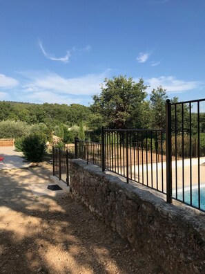 A stone wall with a metal fence, a swimming pool, and a clear sky. - House 'La Bastide de l'Olivier' with Provençal Charm and Private Pool at the Foot of Ventoux (Flassan)
