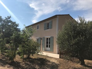 A two-story building with a beige facade, green shutters, and a visible front door. - House 'La Bastide de l'Olivier' with Provençal Charm and Private Pool at the Foot of Ventoux (Flassan)