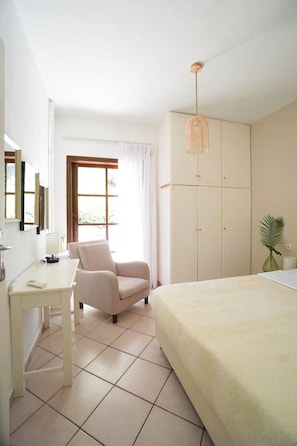 A bedroom with a bed, a chair, a desk, a wardrobe, and a hanging light fixture. - Sea views & full privacy Villa Aetos (Rethymno)