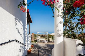 A white building with a view of the sea, a covered outdoor seating area, and potted plants. - Sea views & full privacy Villa Aetos (Rethymno)