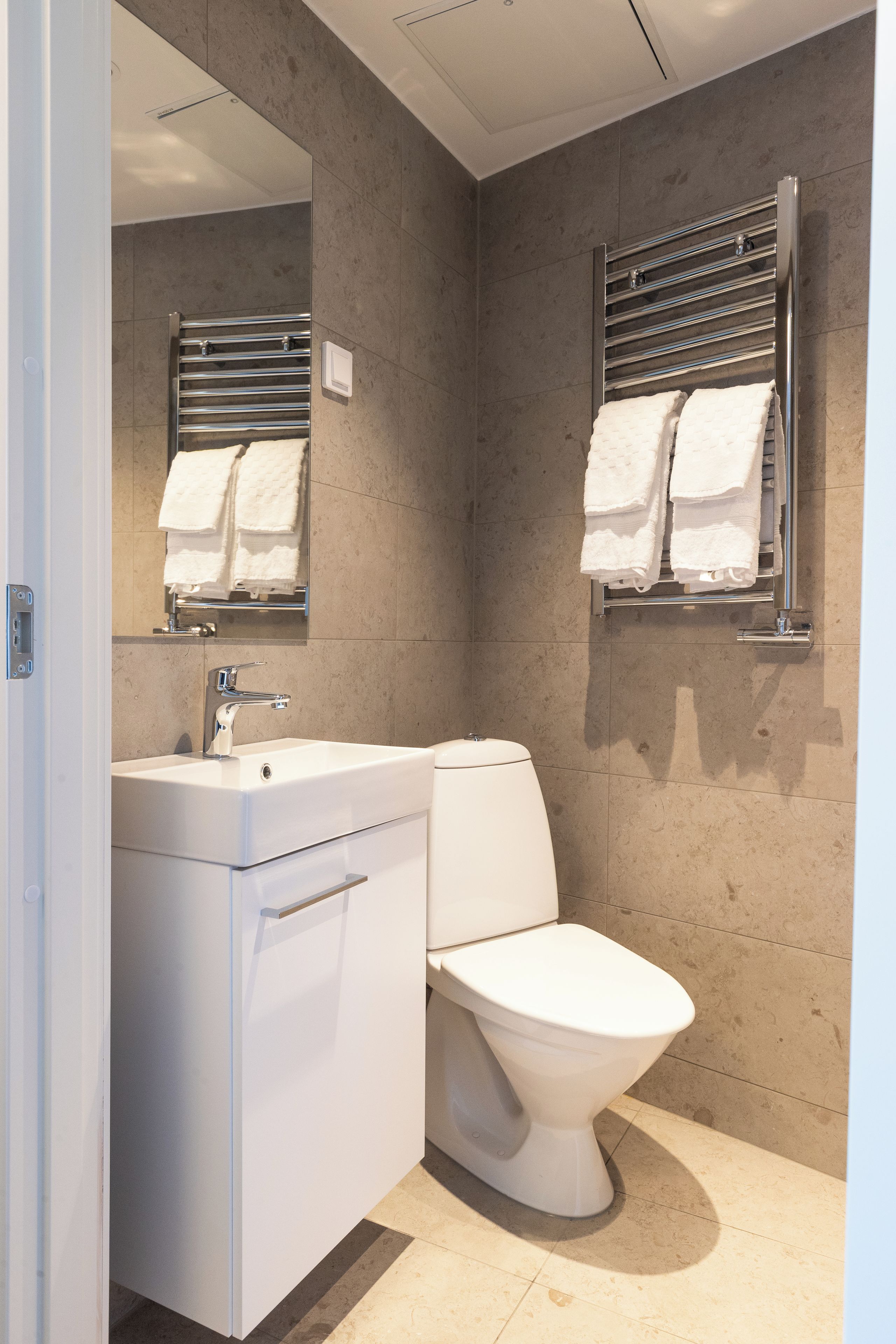 Ein modernes Badezimmer mit einem weißen Waschbecken, einer Toilette und einem Handtuchhalter.