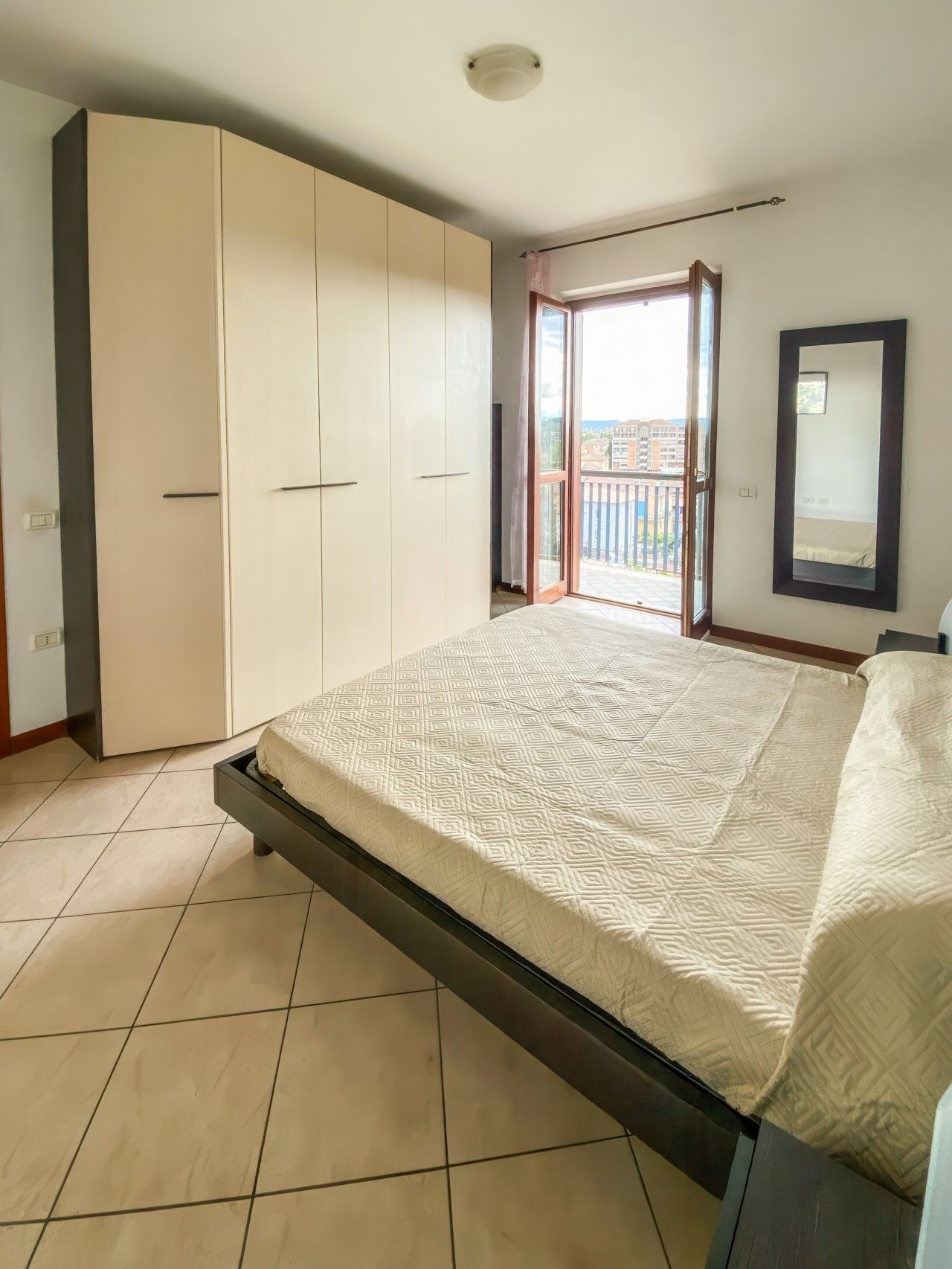 Ein Schlafzimmer mit Bett, Kleiderschrank und einem Balkon mit Blick.