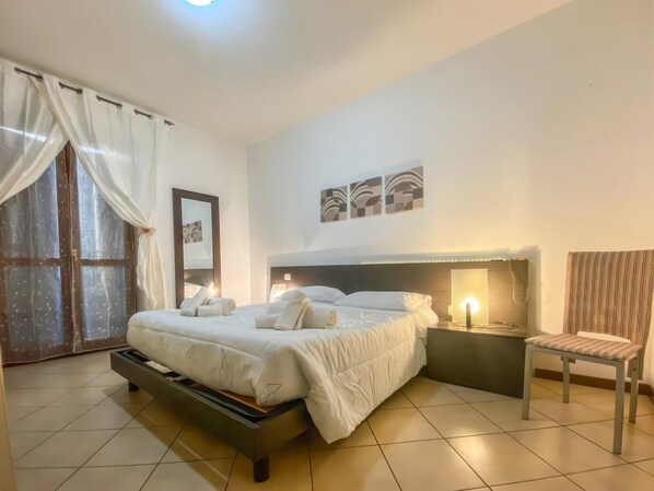 Une chambre à coucher avec un lit, une table de chevet, une chaise et une œuvre d’art accrochée au mur.