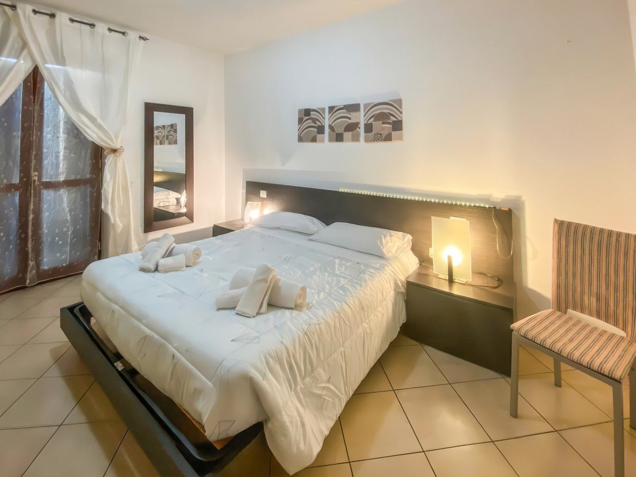 Ein Hotelzimmer mit einem Bett, einem Sessel, einem Nachttisch und einer Wandlampe.