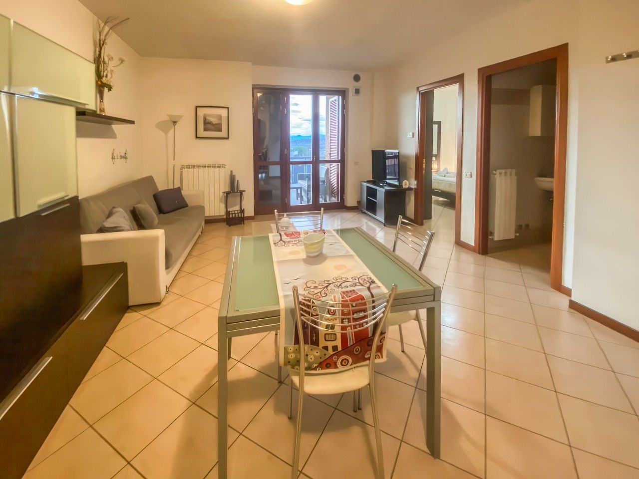 Ein Wohnzimmer mit Esstisch, Stühlen, einer Couch und einem Fernseher.