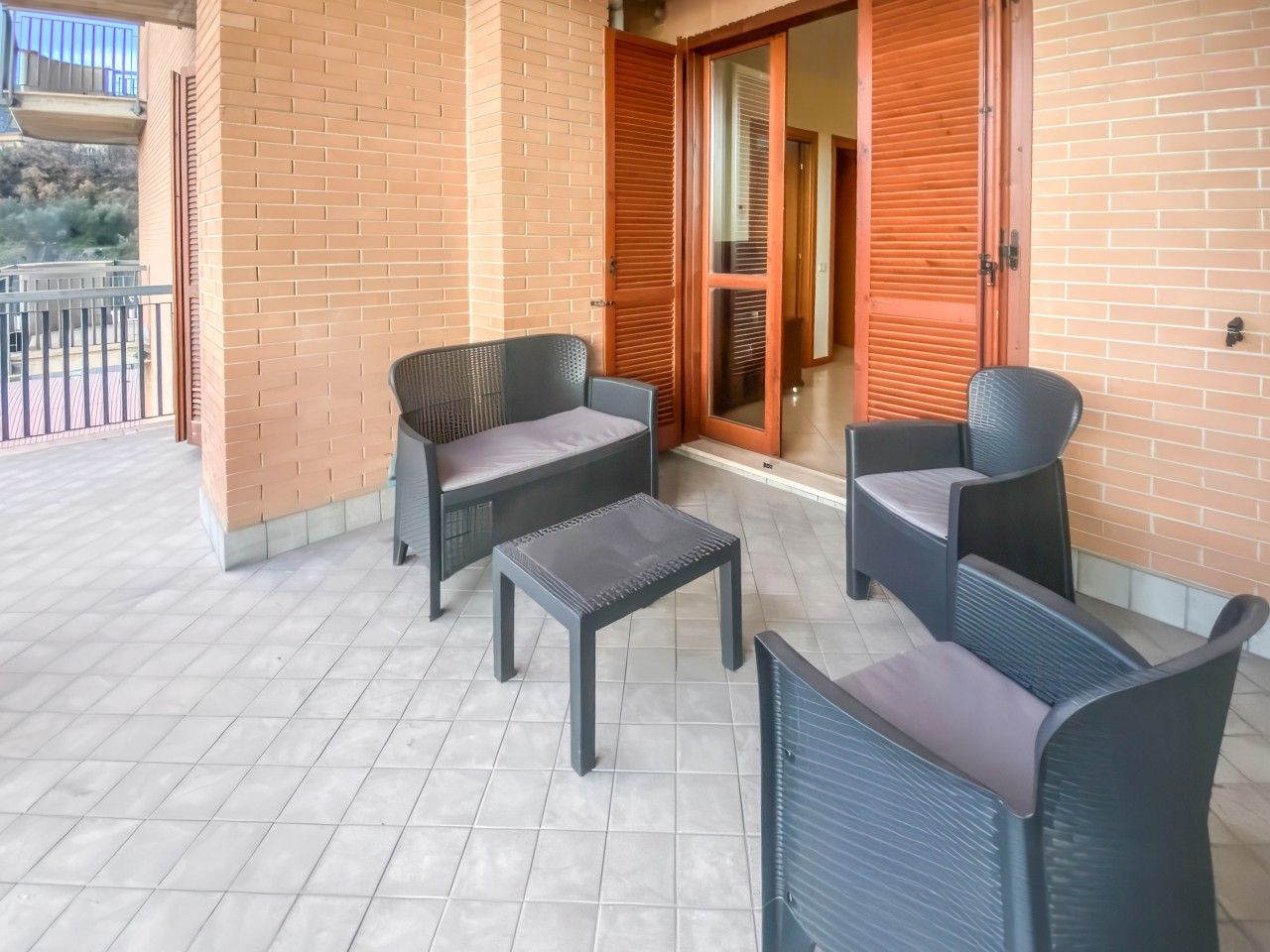 Un balcon agrémenté de meubles en osier, une petite table et une porte-fenêtre coulissante donnant sur une pièce.