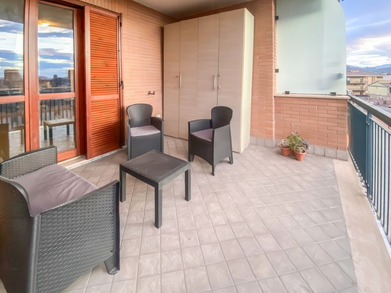 Un balcon doté d’un espace salon, comprenant deux chaises et une table, ainsi qu’une grande armoire.