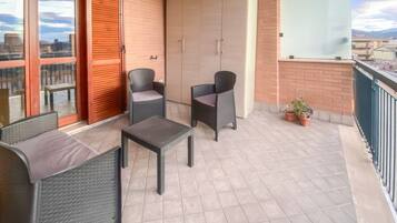 Un balcon doté d’un espace salon, comprenant deux chaises et une table, ainsi qu’une grande armoire.