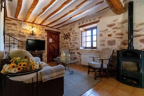 A cozy living room with a fireplace, stone walls, a television, and a comfortable seating area.