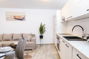 Una cocina moderna con armarios blancos, un lavamanos negro y encimera.