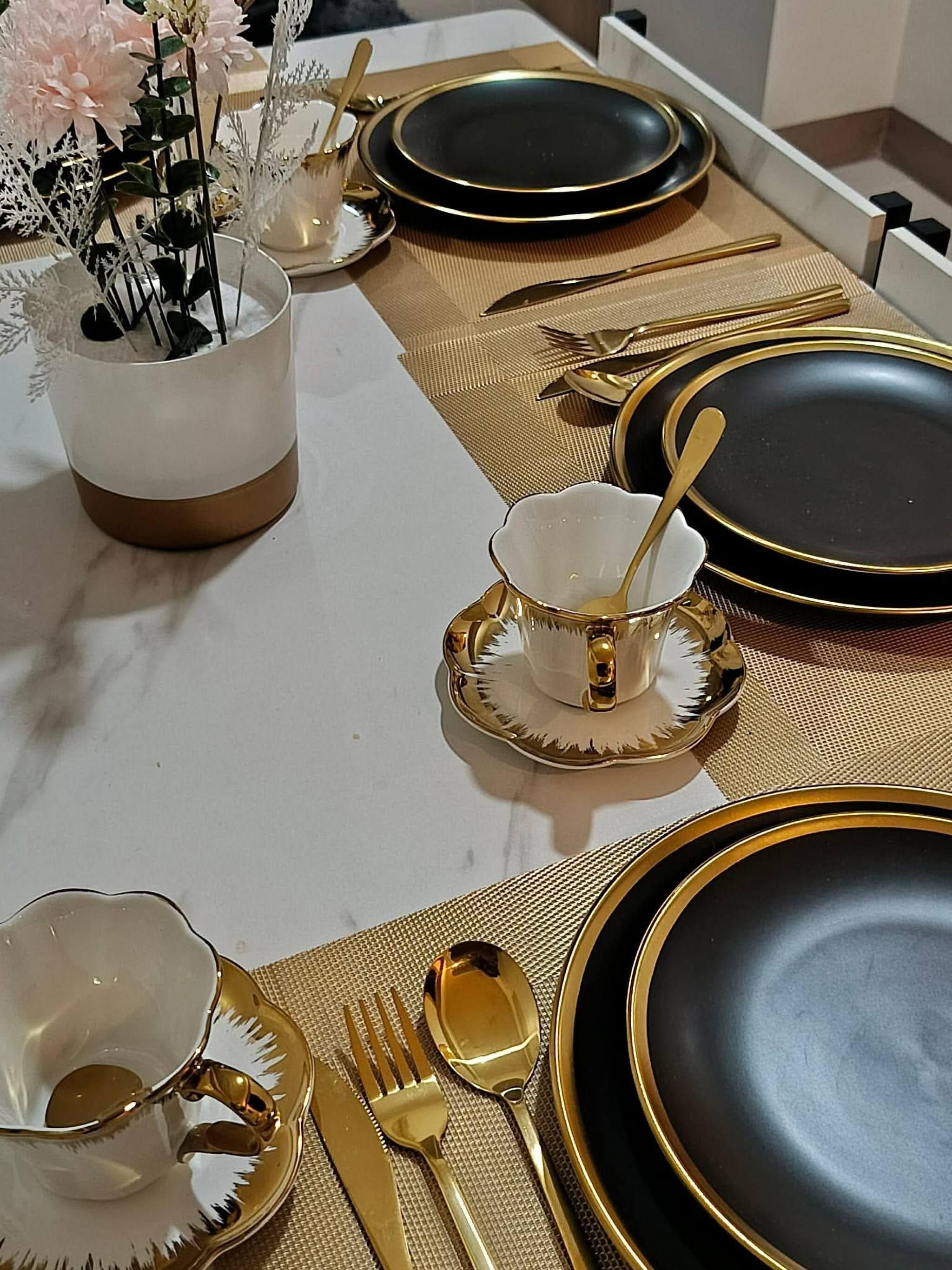 A table set with gold and black dinnerware, including plates, bowls, and cutlery.
