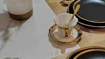 Una mesa puesta con vajilla dorada y negra, que incluye platos, boles y cubiertos.