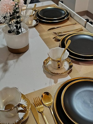 A table set with gold and black dinnerware, including plates, bowls, and cutlery. - Modern, Comfortable Apartment in Central Pasay, Philippines (Pasay)