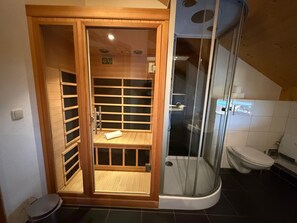 Ein Badezimmer mit Duschkabine, Toilette und integriertem Einbauschrank.