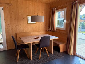 Een houten interieur met een bank, tafel en stoelen.