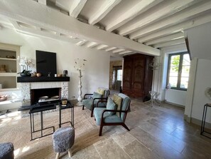 A spacious living room with a fireplace, comfortable seating, and a view of the outdoors. - Maison Marguerite (Gigny)