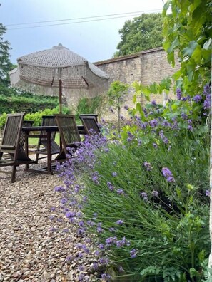 A garden area with a gazebo, a table with chairs, and purple flowers. - Maison Marguerite (Gigny)