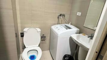 Un baño pequeño con inodoro, lavadora y lavamanos.