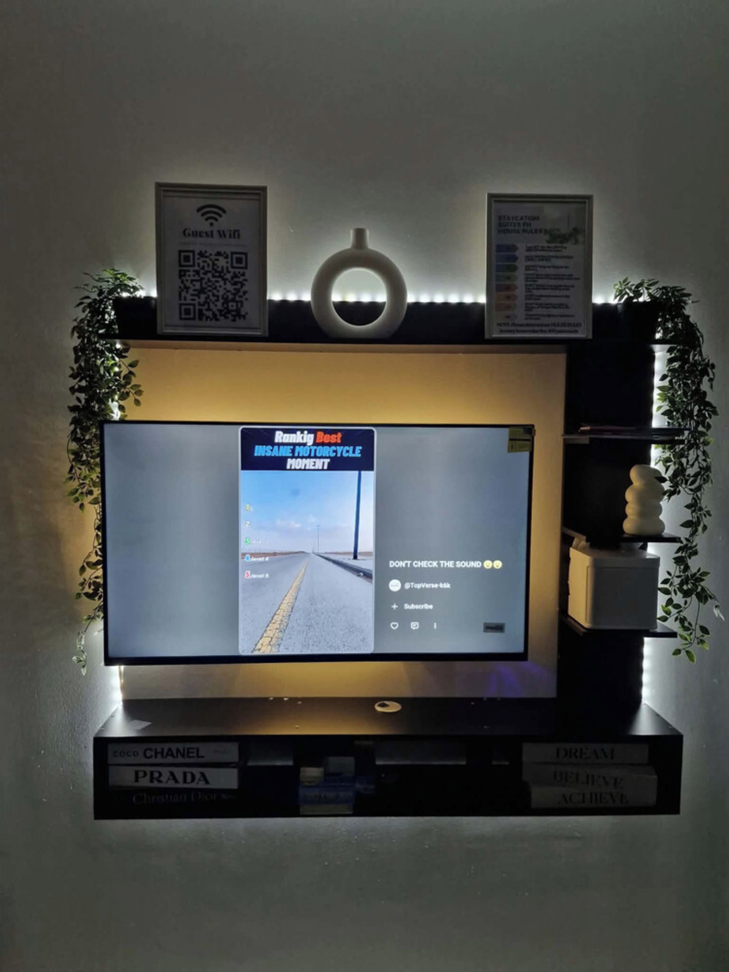 A television mounted on a wall with a 'Rankig Best Insane Motorcycle Moment' video playing.