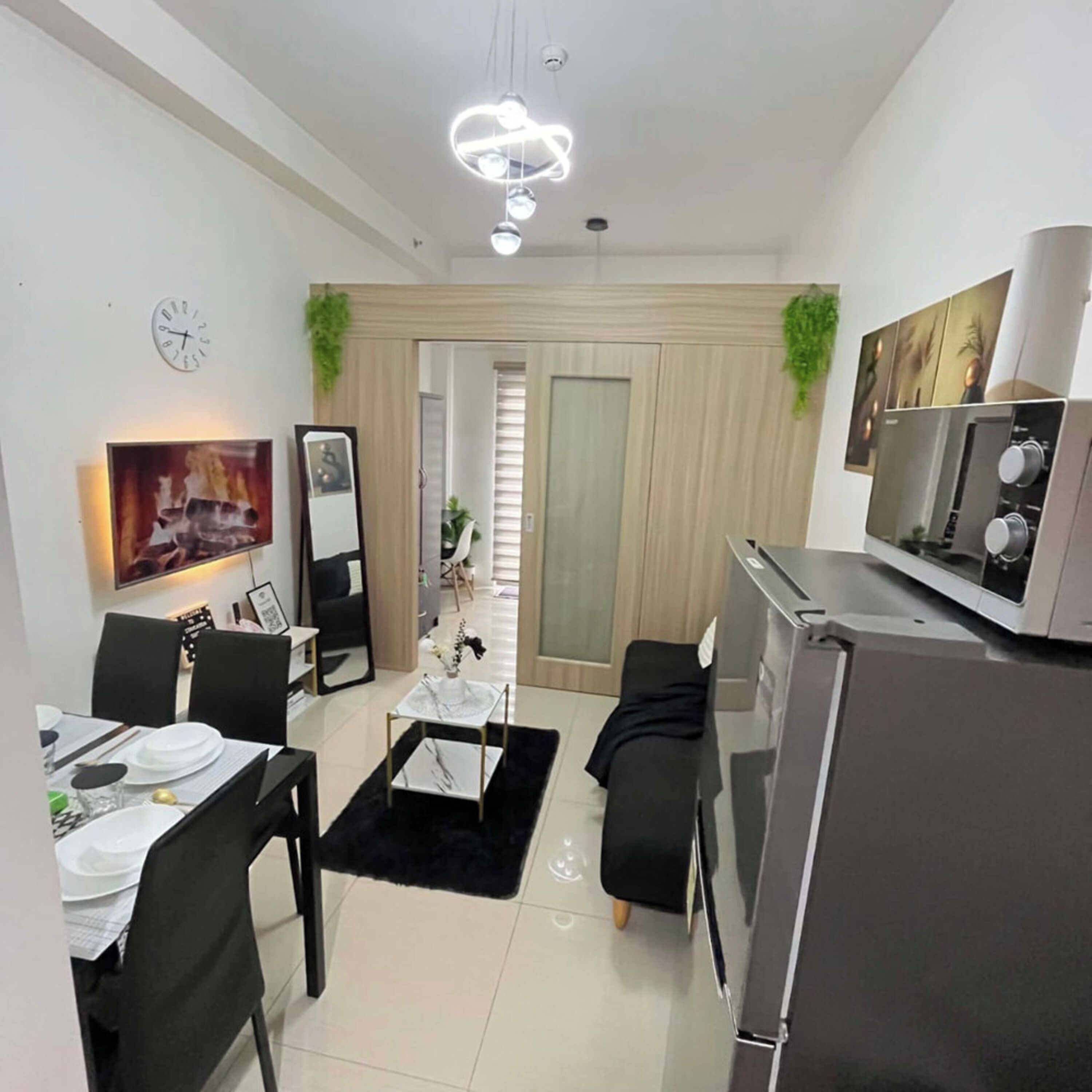 A modern living room with a dining area, a kitchen, and a large mirror.