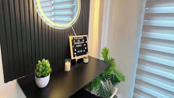 Un comptoir d’accueil agrémenté d’un miroir rond, d’une pancarte de bienvenue, d’une petite plante en pot et d’une bougie.