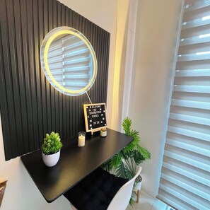 A reception desk with a circular mirror, a welcome sign, a small potted plant, and a candle. - Staycation Suites PH (Pasay City)