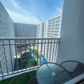 A balcony with a view of high-rise buildings and a pool area. - Staycation Suites PH (Pasay City)