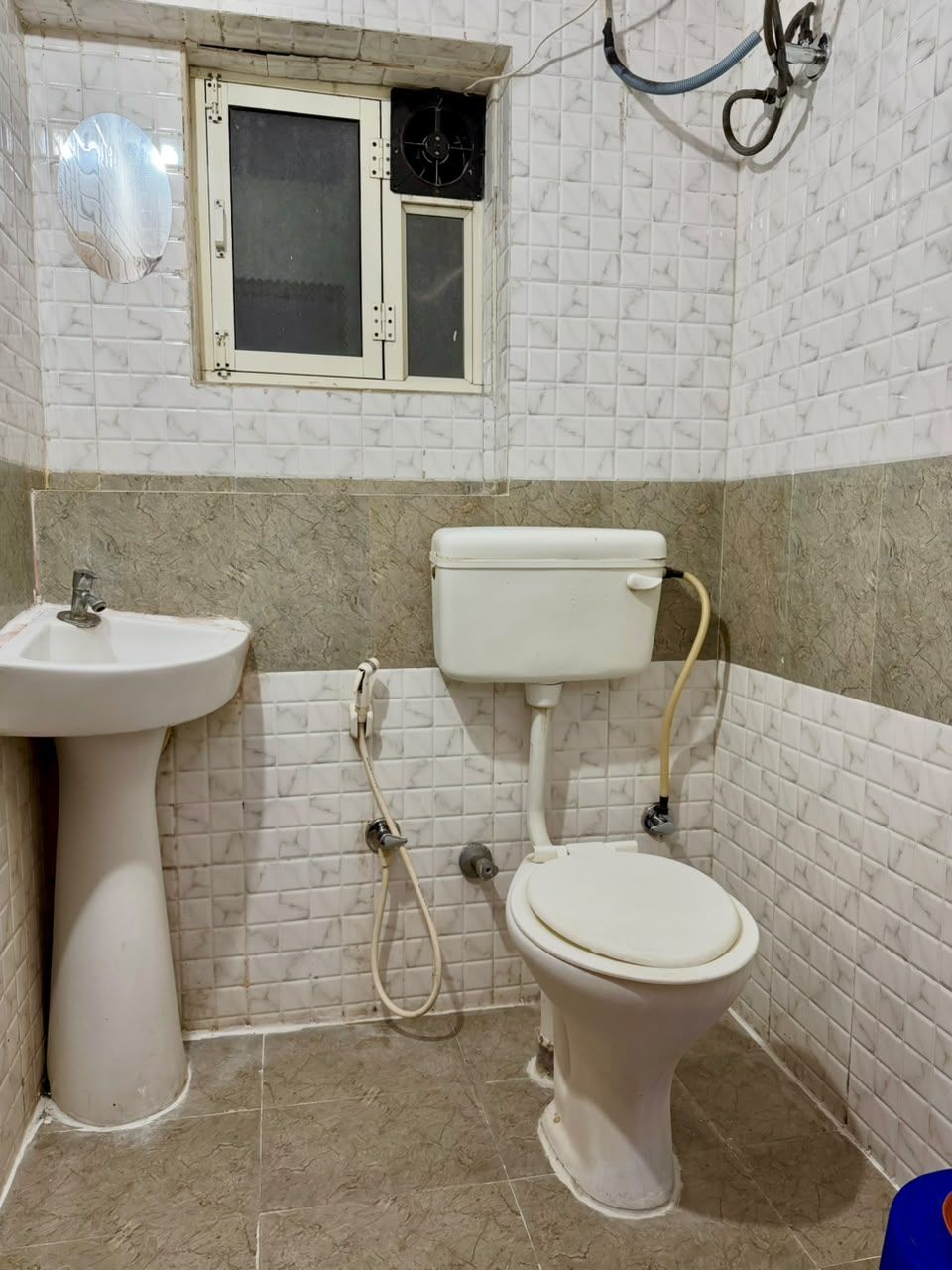 A bathroom with a toilet, sink, and window.