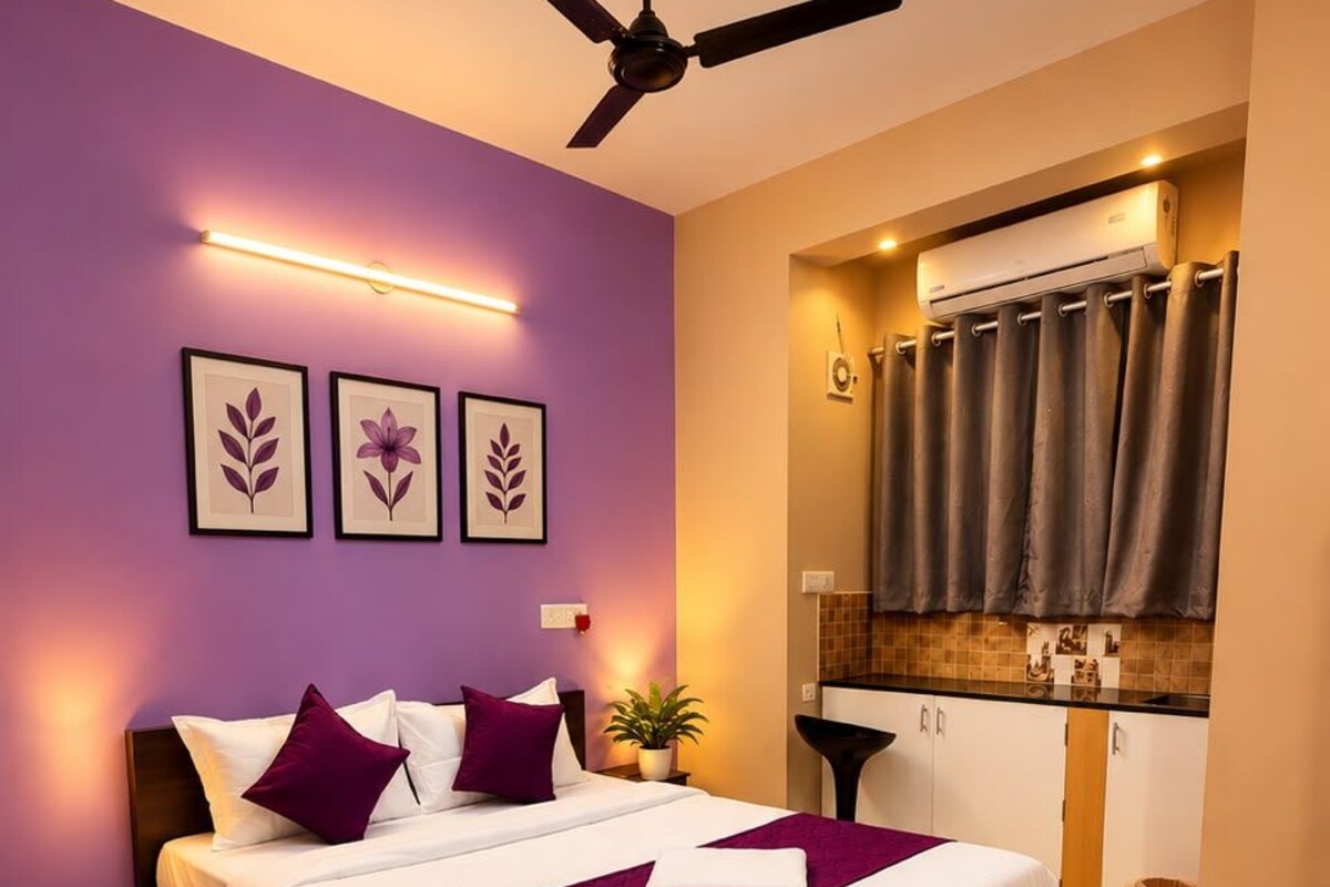Un dormitorio moderno con cama, ventilador de techo y kitchenette integrado.
