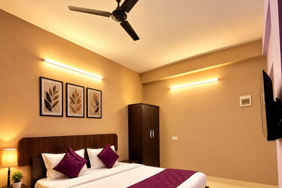 Una habitación de hotel con una cama grande, ventilador de techo, armario e iluminación en la pared.