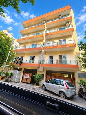 A multi-story hotel with balconies, a parking area, and a sign indicating a sale.