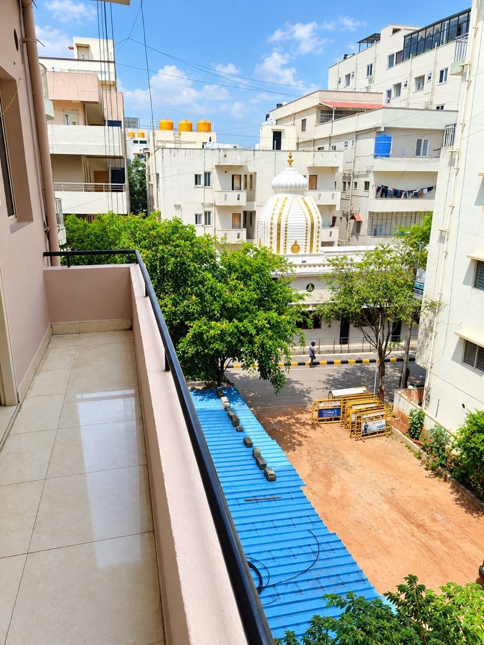 A residential area with multi-story buildings, a blue-roofed structure in the foreground, and a white building with a dome in the background.