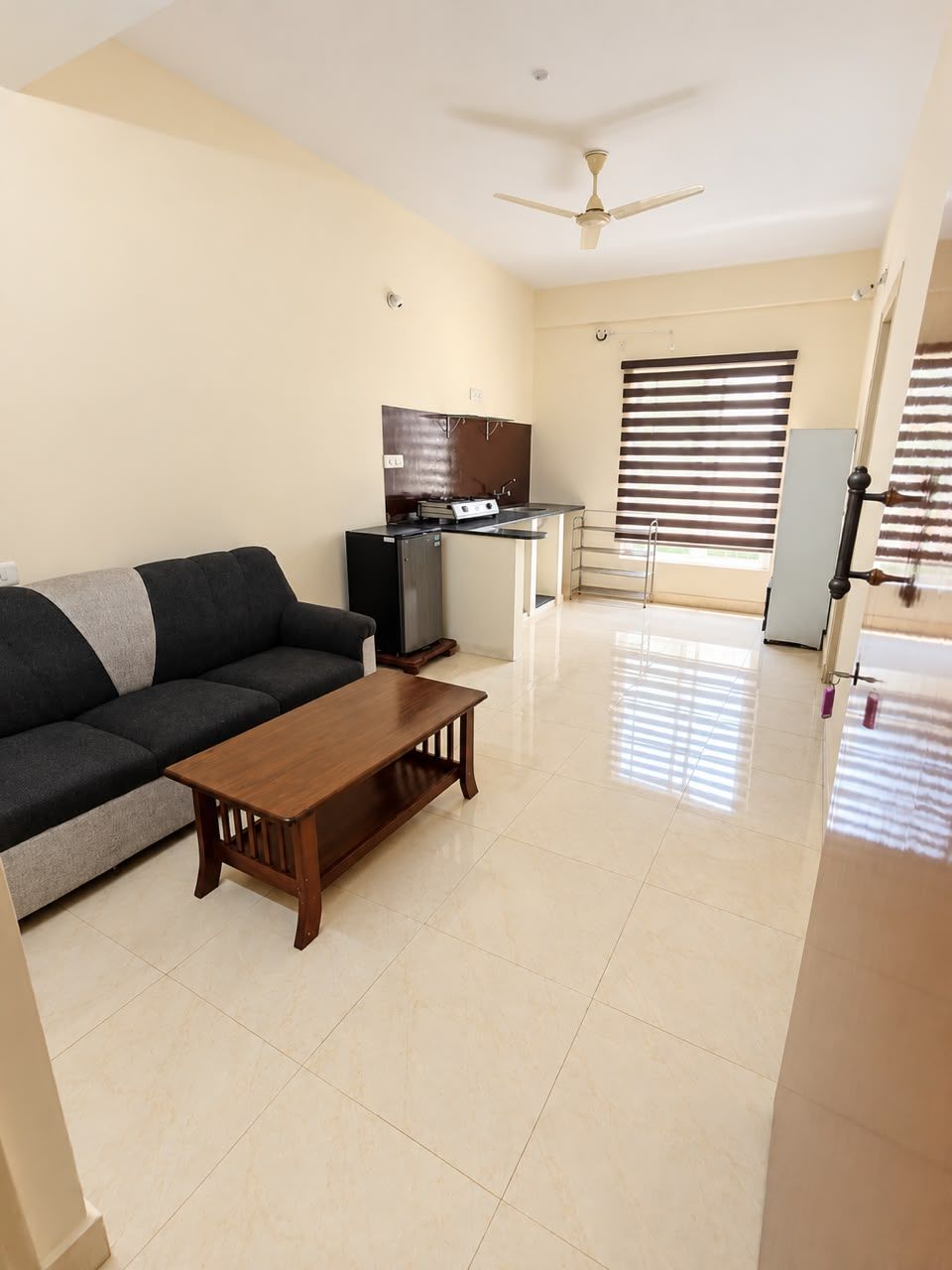 A living room with a sofa, coffee table, and a kitchen area with a stove and cabinets.