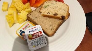 A meal with mixed fruit jam, pineapple, watermelon, and bread on a plate.