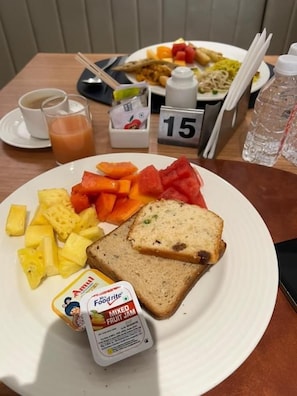 A meal with mixed fruit jam, pineapple, watermelon, and bread on a plate.
