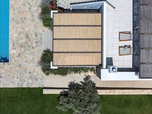 A modern building with a stone facade, a rooftop terrace with a wooden deck, and a swimming pool. - Villa Elies be a part of Crete (Mesi)