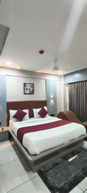 Habitación de hotel moderna con una cama grande, una mesita de noche, una silla y un ventilador de techo.