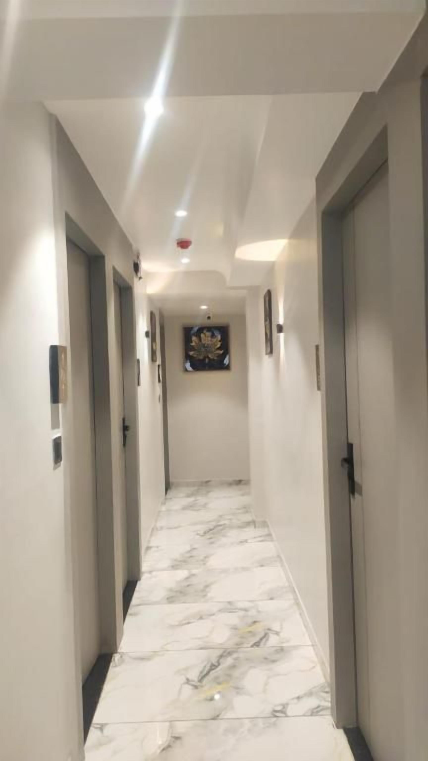 A hallway with marble flooring, doors on both sides, and a ceiling light.