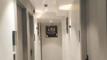 A hallway with marble flooring, doors on both sides, and a ceiling light.