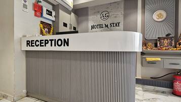 A reception desk with a sign that reads 'RECEPTION' and a 'HOTEL M STAY' sign above it.