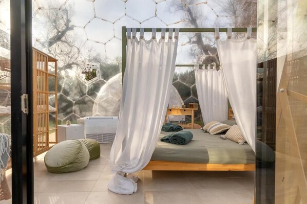 A bedroom with a bed, a bedside table, a chair, and a window with a view of trees.