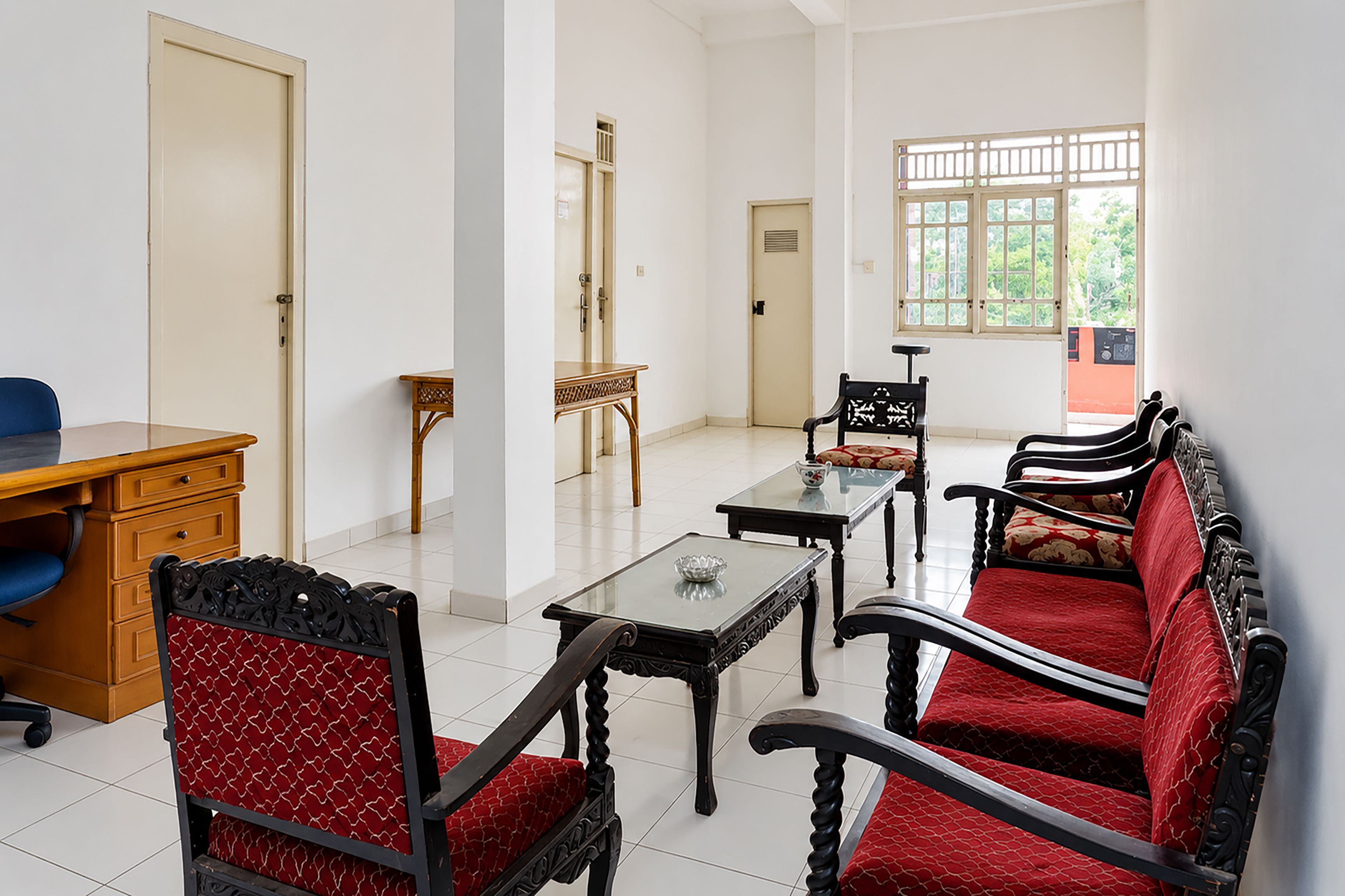 Una habitación con escritorio, dos sillas, una mesa y un sofá.