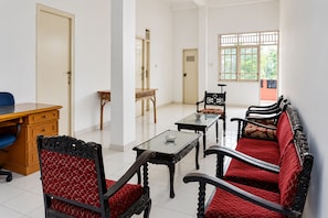 Um quarto com escrivaninha, duas cadeiras, mesa e sofá.