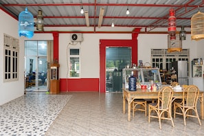 Quarto com chão em mosaico, mesa com cadeiras, geladeira e janela com vista.